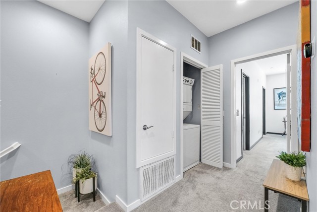 Upstairs hallway with stackable washer/dryer area on left and 2nd bedroom straight ahead.