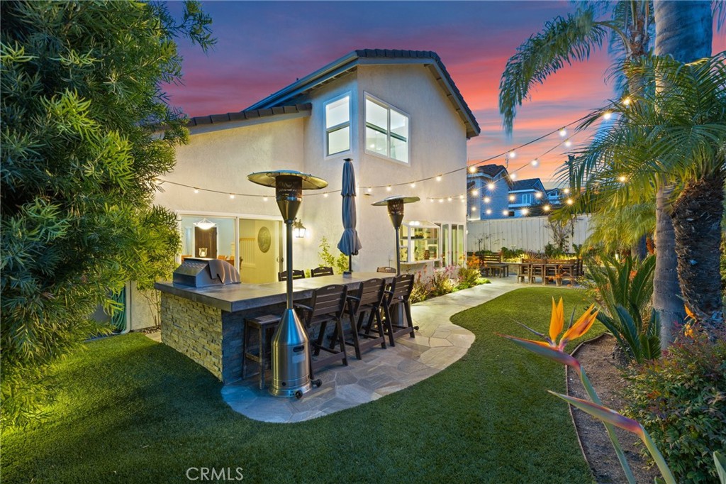 Welcome to this beautiful tropical themed home with 4 bedrooms and 3 baths! This floorplan offers a convenient bedroom and a remodeled full bathroom on the main level! This cul-de-sac home has a bright and airy feel and is perfect for entertaining! Upon entering, you'll be greeted by a spacious living room and adjoining dining room with soaring ceilings and large slider doors that provide seamless access to the backyard oasis. The renovated kitchen features quartz countertops, upgraded cabinetry with convenient pantry pull-outs, recessed lighting, a central island, and top-of-the-line stainless steel appliances. The kitchen flows into a cozy dining nook and a generously-sized family room with a gas fireplace including a custom stone mantle and built-ins, creating the perfect space for entertaining.  The staircase has designer touches including a granite shelf downstairs and lighted showcase niche halfway up. Upstairs, you'll find the luxurious primary suite, complete with dual walk-in closets and a spa-like bath with a dual vanity, separate tub, shower, and heated towel rack. Two additional bedrooms are also on the upper level, along with a beautifully updated full bathroom featuring a new tub and a rain glass enclosure. Step outside into the professionally hardscaped backyard, designed for both relaxation and entertaining. Accessible from both the dining room and kitchen, the backyard includes a stone BBQ bar, long grassy yard and a large seating area to enjoy the picturesque hill views—perfect for hosting guests or enjoying a quiet evening. The side yard has a gated dog run area as well. The 3-car garage offers workbenches, cabinets, overhead storage, and a newer water heater. Great schools, cool breezes, and just minutes from pristine beaches and Dana Point Harbor, this home offers the perfect blend of comfort, style, and location. Don’t miss out on the chance to make this gem your own!