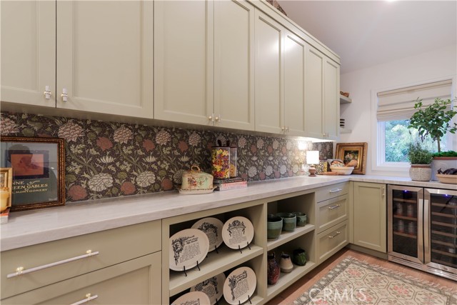 Exceptionally large walk in pantry featuring extensive storage, a built in beverage cooler and a convenient drop station designed to keep everyday essentials organized while maintaining a clean, sophisticated kitchen esthetic.