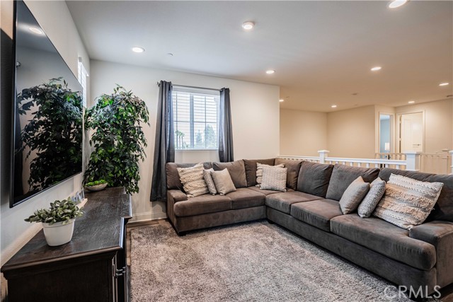 Loft upstairs is right at the top of the staircase. A magnificent place for movie night. Tons of recessed lighting and wood laminate flooring. Sellers chose to place a cozy carpet underneath. You can see palm trees and views from the window!