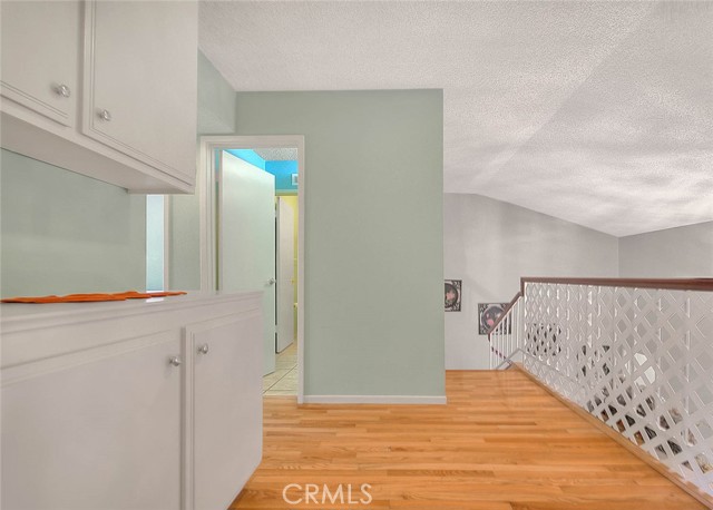 Top Of Stairs Hallway.  Solid Wood Flooring Continues To Entire Second Floor. Cabinet Space Galore.  Middle Door Leads To 2nd Full Bathroom.  Latticework On Railing For Small Kids & Pets--Easily Removed