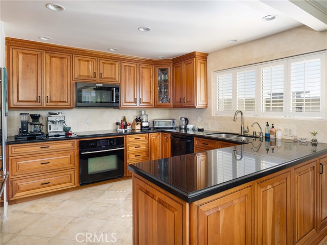 Beautifully remodeled kitchen with granite counters, high-quality cabinetry, and travertine floors
