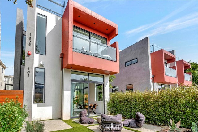 1329 California Avenue 101 Santa Monica, California The award winning, William Adams, has created another architectural masterpiece. This north of Wilshire detached new construction is now available. Every angle of this home has been artistically rendered. The landscaping has been strategically planted to create intimate spaces while still being close to it all. Sunlight moves throughout the home like art work, reflecting off the perfect mix of glass, warm redwood and fine industrial finishes. From curbside to rooftop, this home is a stunner.
Walking through the expansive glass entry door you’ll be wowed by the dramatic lines and open concept this home delivers. Flooded with natural light- the main level hosts a high end kitchen with Miele appliances and Bulthaup cabinets.The kitchen is finished with an abundance of cupboards, drawers and a kitchen island accented with a walnut toned breakfast bar. A thoughtfully designed custom pantry with butcher block counters offers plenty of additional storage.
Gallery worthy walls, recessed lighting, concrete floors in a terrazzo style add to the warm industrial modern vibe of this Santa Monica townhome.
A modern corner fireplace warms the living and dining spaces. Glass telescoping doors open to a private use front patio which extends the living space to the outdoors. Both the patio and expansive rooftop deck are plumbed for gas, allowing flexibility while entertaining and grilling.
The mezzanine offers additional entertaining space, a movie room, gym, game room… It’s as flexible as your imagination. A few steps above the mezzanine is the primary bedroom. Located at the front of the home, it’s adorned with a private balcony and walk-in closet. The primary bathroom is a delight with gorgeous floating, walnut toned cabinets, a large glass walled shower and separate tub. Two undermount sinks are complemented with clean linear white quartz counters.
A few steps up lies a spacious secondary bedroom and bathroom. The laundry area is located on this level as well as an open space, perfect for a home office or play zone. This space could also be converted to a 3rd bedroom.
The large private rooftop deck rests one flight up. Boasting views of the surrounding area, this space provides an additional outdoor area to enjoy the Santa Monica weather.
Further benefits of the home include a spacious attached two car garage with bike room, two private side yards, custom automated shades and smart wiring throughout. This open concept masterpiece awaits you.