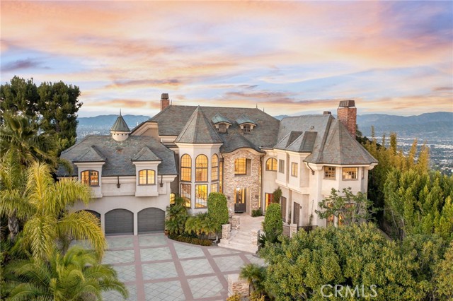 Introducing an impressive French Chateau perched on the crest of one of the most scenic roads in the U.S., Mulholland Drive. Perfectly poised for outstanding 360-degree views from ocean sunsets to sparkling city lights and the Santa Monica mountain skyline.

Enter through double doors into the dramatic 2-story foyer that immediately captivates with a stunning dining room, a gorgeous winding staircase, and natural light pouring in from its 30-foot windows. Offering an unmatched living experience, the Chateau features three breathtaking balconies of expansive views.

Boasting over 9,300 square feet of an idyllic layout that balances spaciousness with warmth. This iconic home offers three beautiful living rooms, formal and informal dining rooms, 5 bedrooms, 7 bathrooms, and 5 uniquely stunning fireplaces. The primary bedroom is a luxurious retreat with a romantic fireplace, a scenic sitting area, an oversized hot tub with 180-degree views, two separate en-suite baths, two walk-in closets, and French doors that lead you to an incredibly serene balcony that takes you a world away. The kitchen is outfitted with top-of-the-line appliances, a large stone island, and a curved wall of elegant french windows that make for an exceptional dining experience.

Distinguished details include soaring ceilings, limestone floors, and an alluring library of rich solid redwood with a majestic hand-carved fireplace and unparalleled city views. Set behind a private gate, on 3/4 of an acre, complete with lush landscaping, a putting green, swimming pool, spa, pool recreation room with shower, plus an outdoor kitchen with built-in barbecue overlooking the fireplace and ambient waterfall. The property also offers garage space for 3 cars and driveway space for six more. This iconic property is one of a kind and sits above some of the most exclusive neighborhoods in the world.