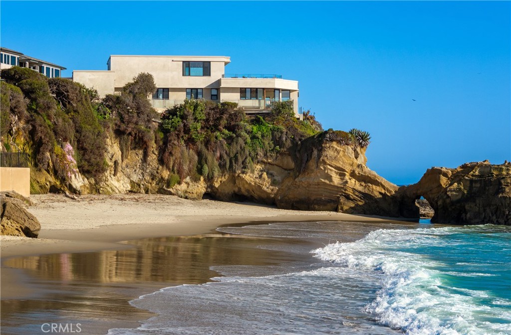 Set in what is arguably the most scenic oceanfront location in Laguna Beach, this iconic residence is set atop the landmark outcropping known as the famed Arch Rock. This private peninsula, reached only via a gated private drive, affords a singular setting with unobstructed 270 degree views of the crashing surf, coves, sunsets and nearly one hundred miles of coastline. The view found here is simply without equal. The extraordinary home created on here is an appropriate complement to the even more extraordinary site. Its tasteful contemporary design was reimagined and rebuilt in recent years with finest materials and is presented in flawless condition. Enveloped in floor-to-ceiling glass walls, every main room has a view up and down the coast. A central great room opens to a protected courtyard terrace suspended above the water (one of seven), and adjoins the entertaining kitchen and formal dining room. Upstairs, the full-floor master suite seemingly floats above the ocean and opens to an extraordinary private view terrace. Two other guest suites (one as a guest house) complete the main areas of the home. All of one’s senses come alive when in residence, as one can experience the varied scents of ocean’s salt spray, the golden rays of the afternoon sun, and the alluring and hypnotic sounds of waves crashing on the shore. One can easily imagine a relaxed life here, surrounded by friends and family, enjoying the ocean throughout the year. A private stair that descends to the coves below provides immediate access to miles of pristine coastline. This location in the highly desirable neighborhood of Woods Cove allows for leisurely walks to morning coffee, while also affording easy pedestrian access to the myriad shops and restaurants of this beloved coastal village.