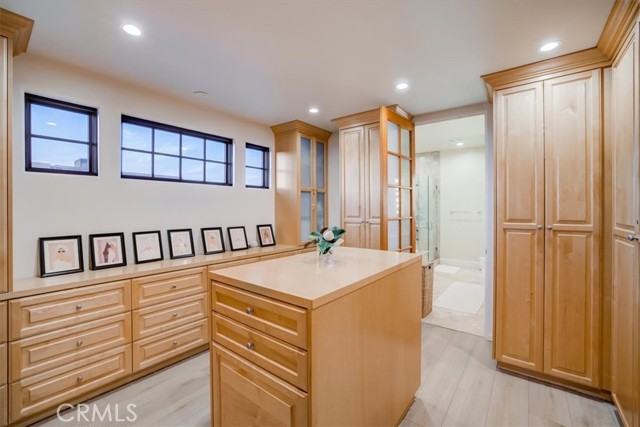 Organized and clean walk through/walk in closet suited with custom cabinets and an island.