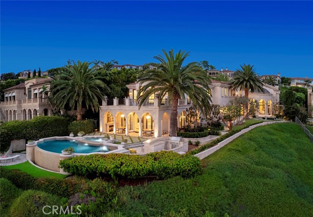 Situated on a prized front-row lot, this Pelican Crest showpiece estate was newly refreshed in late 2023 and enjoys unobstructed views of the Pacific Ocean, Catalina Island, Newport Harbor, Pelican Hill Golf Course, spectacular sunsets, and twinkling evening lights. Bespoke transitional interiors of nearly 14,200 square feet provide unsurpassed comfort and hosts seven bedrooms and twelve baths. Authentically detailed architecture, romantic archways, columns, domes, and Palladian windows work in tandem to create first impressions that will last a lifetime. A phenomenal entry with custom glass and iron door sets the scene and introduces airy galleries, a library, formal living room, and lavish guest suite complete with a private sitting room. Awaiting at the heart of the home is a two-story oval foyer which reveals a dramatic staircase, formal dining room for both grand-scale and intimate entertaining, and a spacious great room with six sets of French doors that open onto a fireplace-warmed loggia. Grandeur is elevated to lofty new heights with custom lighting, multiple interior and exterior staircases, impressive fireplaces, and one-of-a-kind flooring. Catering to professional and amateur chef’s alike, the gourmet-inspired kitchen complements timeless style with a butler’s pantry, center island, and a breakfast area. From romantic evenings at home and impromptu gatherings to formal affairs that are destined for the social pages, the generous floorplan offers three service bars and accommodates every occasion with style and sophistication. An elevator serves all four levels, including a basement with an eight-car garage, game room, gym, sauna, and steam shower. Take the stairs or elevator down to the sub-basement where a 34' indoor swimming pool is destined to be a favorite place for all who visit. Captivating ocean vistas embellish the owner's suite, where a large view terrace, sitting area, fireplace, dual walk-in closets, separate vanities, and a glamorous soaking tub fulfill the residence's promise of delivering uncompromising luxury. Lushly landscaped grounds recall the beauty of an exclusive Mediterranean resort, where graceful palms, broad lawns, and sunny patios are joined by a sublime ocean-view swimming pool and spa. Set just moments from championship golf courses, five-star resorts, high-end retail, and upscale dining, 14 Channel Vista represents a truly rare offering.