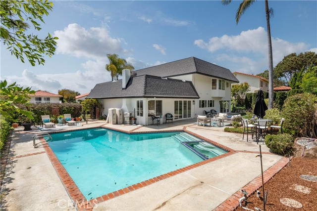 Enclosed backyard with grass, patio, pool.