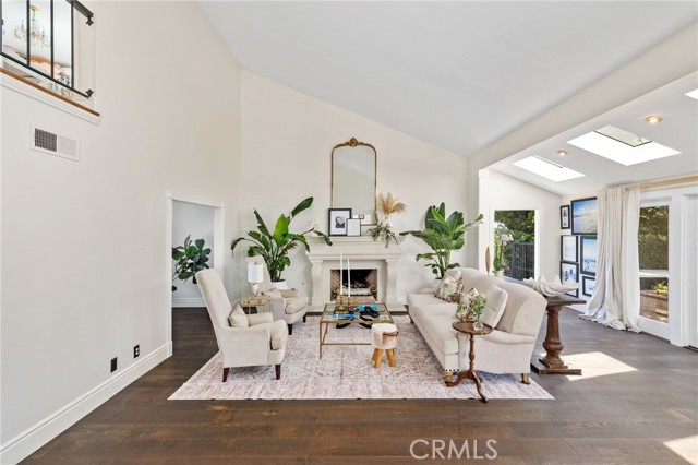 The formal living room with soaring vaulted ceilings, a romantic custom fireplace, and wide plank French oak floors.