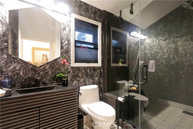 The sophisticated black guest bathroom with dramatic finishes, designer lighting and a sleek modern esthetic will impress your most discerning guests.