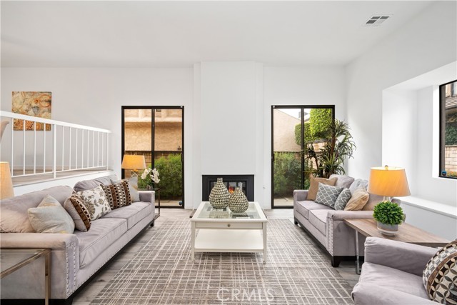 Large welcoming living room with  10 foot+  high ceilings, fireplace and lots of lighting from the south facing patio/ back yard area.