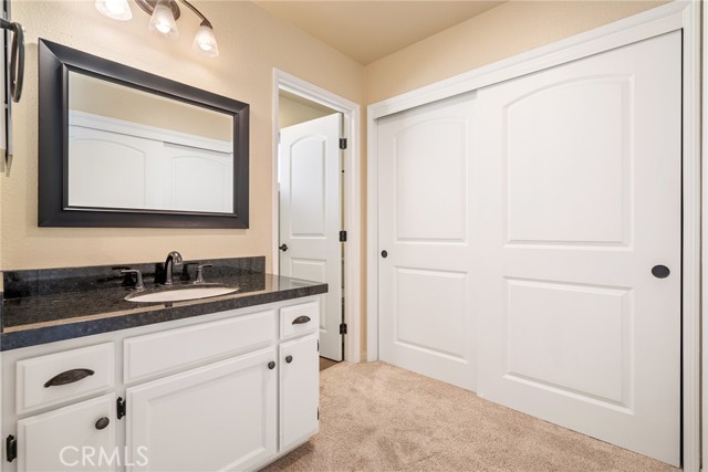 Connected to the primary bedroom is the ensuite bathroom. The sink area has a granite countertop vanity and a built in medicine cabinet.