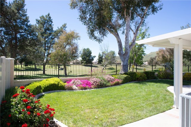 Rear covered patio, manicured lawn and colorful gardens overlooking the golf course.