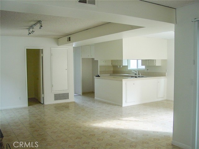 A photo from the laundry area showing the dining area, the family room, the kitchen and the door to the left goes to the downstairs half bath.