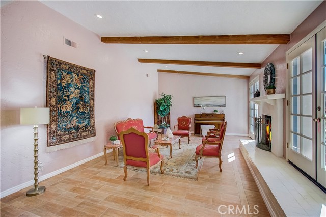 Open and bright formal living room with cozy fireplace and 2 sets of French doors leading out to your pool deck!