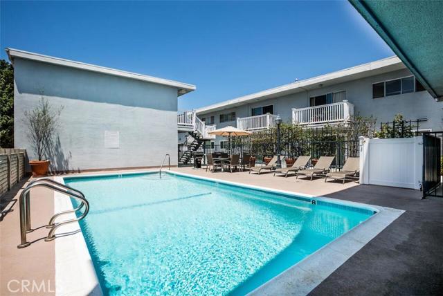 common area pool area with updated lounge chairs, table and umbrella.