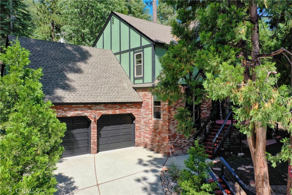 Welcome to this Charming Tudor Style Home with it's traditional brick and wood timbering facade, a favorite hallmark of tudor style architecture. You will joyfully be surprised with the light and airy rooms and turnkey perfection remodel just completed. Nestled in the sought after upscale summit area adjacent to Lake Arrowhead Golf Course and Country Club there is easy access to fairway and cart path just around bend.  Perched on a gentle knoll with over a quarter acre, one of the many highlights of this newly updated home is the large and private rear yard wonderland.  Just choose your hobby!  Bocci ball, horse shoe pit, a putting green, sustainable gardening, Fido and friend's play yard, and even a children's fort house could all be created with one's creative imagination.  All the while, wrap around decking and seating areas abound with privacy and are easily accessible for entertaining. Try farm to table dining as an option.  Enhanced with curated designer touches throughout, providing an eclectic Farm House inspired vibe, the main entry foyer with vaulted ceilings opens to a comfortable living room area with a german smear brick fireplace, board and batten walls, also freshly painted and floored, Then welcome to the huge dining and kitchen area which offers seating for up to 15 guest with two dining areas, a floating island,  and a built in coffee station.  New stainless appliances, lighting fixtures, recessed lighting, butcher block counter tops, tile back splash, and even a barn door enclosure for laundry room have made this once upon dark spaces lighter brighter and better than ever.  A main level "golf inspired" study or home office features a large picture window overlooking the also enjoyable low maintenance front yard area perfect for sun down chill time. The upper level offers 4 generous and well lit bedrooms with walk in closets,  one currently staged as a flexible living space for gaming and tv viewing.  Check out the very generously sized master suite with spa size bath, sitting area, and walk in closet space makes this home totally suitable for full time living.  Sophisticated yet Cali casual and inviting, there's a little bit of personality for everyone.  A beautiful forest of trees, a beautiful golf course, and a beautiful full lake- offered with lake rights, Live and Enjoy A life style enhancement right at your front door!  Kyack, Golf, Boat, Ski, Dine and Shop all in one day!  Just listed to sell Fast, make this home yours today!
