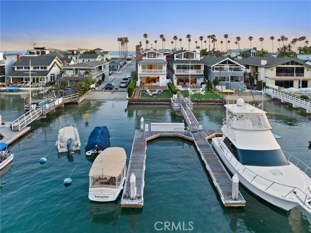 Occupying a most enviable position on Newport Harbor, this recently built bayfront masterpiece by acclaimed William Guidero Design and Winkle Custom Homes personifies our iconic California riviera and the idyllic lifestyle only this prized locale can provide. Meticulously crafted with classic lines and a crisp coastal aesthetic showcasing extraordinary sightlines and abundant light, all delivered in a timeless design language befitting of any discerning buyer. Enjoy ever-changing cinematic views and inspired vignettes from all three floors; Boats gently glide across the shimmering bay, harbor lights give way to postcard worthy backdrops framed by rolling hills and the glittering buildings of Fashion Island as historic Balboa Pavillion anchors the inspired scene. Situated on an exceedingly rare oversized corner-lot, the home features expansive outdoor space as well as a newly-constructed dock able to accommodate a yacht up to 60' feet, in addition to a side-tie. The home itself provides every imaginable amenity with a gorgeous Chef's Kitchen outfitted with best-in-class appliances, and chefs office. The grand owner's suite features a large private balcony, fireplace, spa bath, dual closets and of course views perched above the bay. A library nook, two additional guest rooms both with ensuite baths and separate balcony complete the second floor. The penthouse level is an entertainer's dream; A game and cinema room opens to a large beach-facing deck on one side and the bayfront rooftop terrace on the other. Fully outfitted with an outdoor kitchen, fireplace, and breathtaking views. The finished garage, thoughtfully placed and with soaring ceilings makes for copious storage and potential for a car lift. Top tier audio, visual, security and lighting have all been appointed throughout. An elevator discreetly accesses all three levels of the home. A location seemingly plucked off the map to afford the best of all worlds; A stroll away from the Balboa Village, ferry, beaches, pier, boardwalk, shops, restaurants and more. Unable to be duplicated today due to newer zoning, this opportunity is a resounding one.