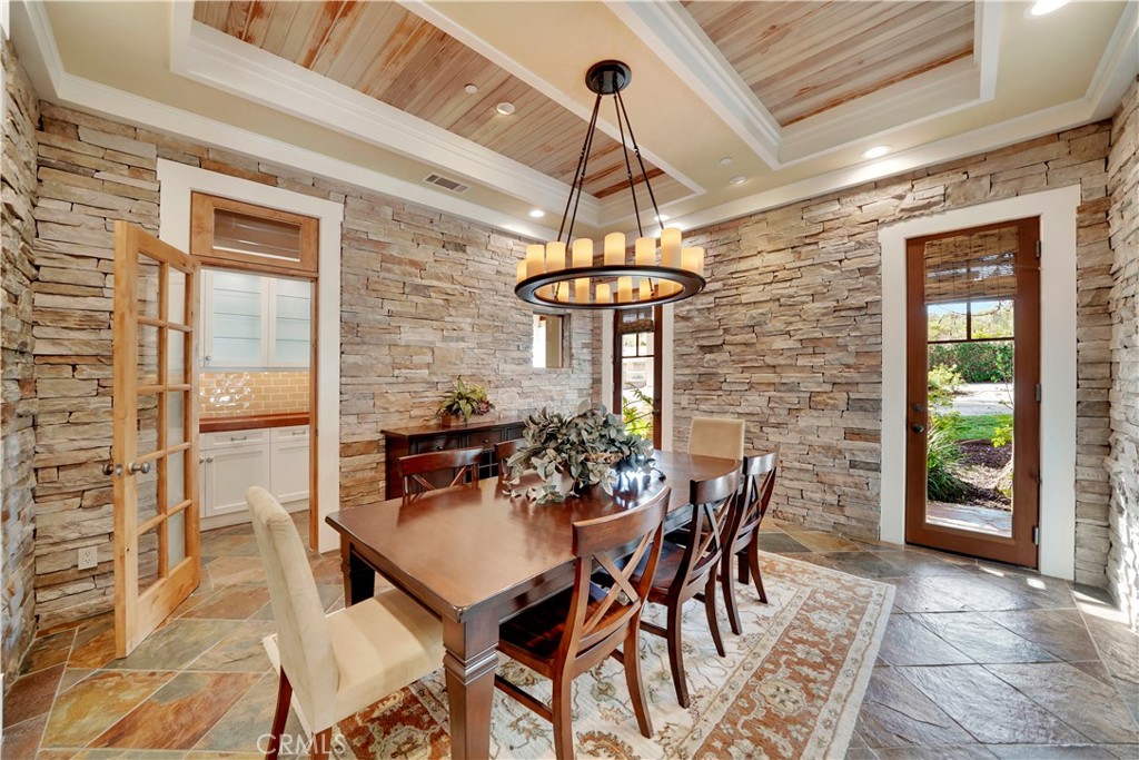 dining room with custom ceiling and stone accented walls