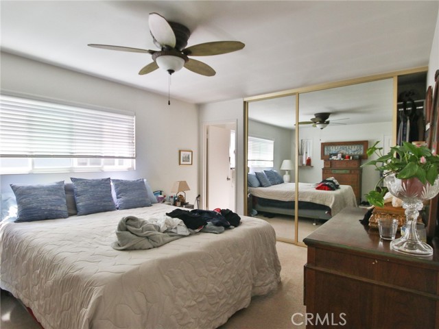 The master bedroom with mirrored wardrobe doors and ceiling fan.  The attached master bath is through door at the back.