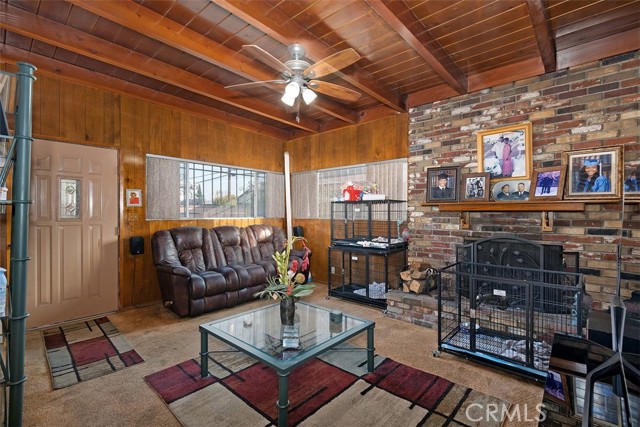 Family room w wood beams and large brick fireplace (dog crates present)