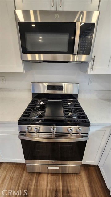 Stove with microwave and hood. Stove has a griddle in the middle