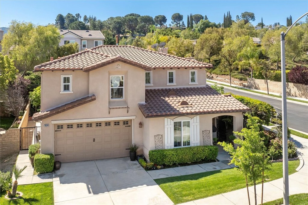 Welcome to this spacious and beautifully designed 5-bedroom, 3-bathroom home, with one bedroom and full bath downstairs, nestled in the Prestigious Canyon Gate gated community on a large corner lot. From the moment you step inside, you’ll be captivated by the open-concept floor plan and custom wrought iron staircase.  With vaulted ceilings and wood-like flooring throughout you will love the abundance of natural light.  A quaint seating area and large formal dining area lead you to the inviting family room that features a cozy fireplace with view of the lush backyard. The open kitchen is a chef’s dream, with ample granite counter space, modern appliances, newer dishwasher and stovetop, large kitchen island and plenty of room for meal preparation and entertaining complete with a breakfast nook area with additional cabinets and counter space. Whether hosting a dinner party or enjoying a quiet family meal, this kitchen is sure to impress. The home boasts five generous bedrooms, offering flexibility for a growing family or the option to create a dedicated home office or gym. The spacious primary bedroom has space for a seating area and features an en-suite bathroom with dual sinks, shower and garden tub and a very large walk-in closet. Down the hall are three additional bedrooms and a full bathroom all with ample space for daily relaxation. Extras include: newer faucets, door handles with heavy metal, dual pane windows, automatic sprinklers, newer HVAC and water heater. Attached 2 car garage. Step outside to your own private oasis with a variety of lush fruit trees-apple, orange, lime, cumquat, guava, grapefruit, mission fig, Asian date, Asian pear, persimmon and a pergola that offers the perfect covered area to enjoy your morning cup of coffee or afternoon refreshment.  The community spa-like amenities include a community pool, spa, clubhouse and BBQ area all within walking distance with a low HOA Fee. Eazy commute as it is located close to the 14 freeway and near the Golden Valley Shopping Center, Costco and great schools with no Mello Roos this property is a must see!