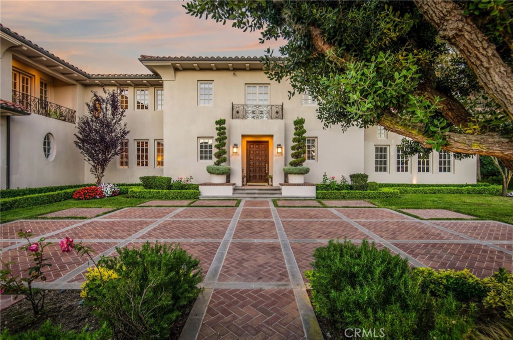 Sited on an over one-and-a-quarter acre lot in the exclusive, guard-gated Bear Brand Ranch community, this Ed Lohrbach-designed estate offers the pinnacle of elegant living. Exuding timeless appeal, the property is a prime example of stately Pasadena-style architecture, with classically scaled interiors and refined sprawling grounds. A soaring double-height foyer with a curved grandeur staircase sets the tone of sophistication prevalent throughout this home. The first floor encompasses formal as well as informal gathering spaces: a dining room, a study, and a sitting room with a magnificent fireplace. A more casual living section opens up to the kitchen with a center island and features sweeping views of the rear yard. The expansive outdoor space offers patios with seating, a pool area with a spa, and elegant meandering pathways set amongst pristine mature landscaping. Grand interiors include four well-proportioned ensuite bedrooms on the upper level, including a sumptuous primary retreat with sweeping views, a sitting area, a fireplace, and a large balcony. Private guest quarters currently utilized as a home office can be accessed via a breezeway, offering seclusion in a multifunctional space. The estate’s sixth bedroom is conveniently located on the ground floor. Impeccable design is evident throughout the stately interiors, with classic millwork, coffered ceilings, and mullioned windows. Exquisitely appointed and located in one of the most coveted enclaves of Orange County, 2 O Hill Ridge presents a truly timeless opportunity.