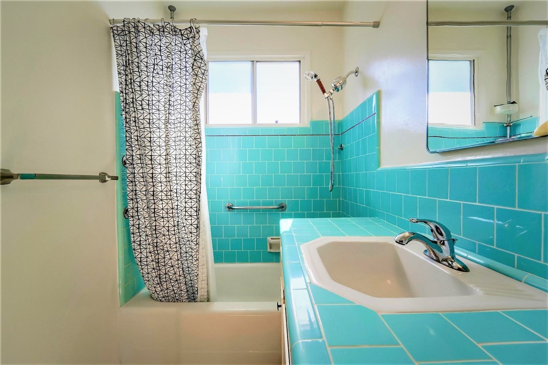 The upper floor full bath has vintage tile and a shower tub combination.