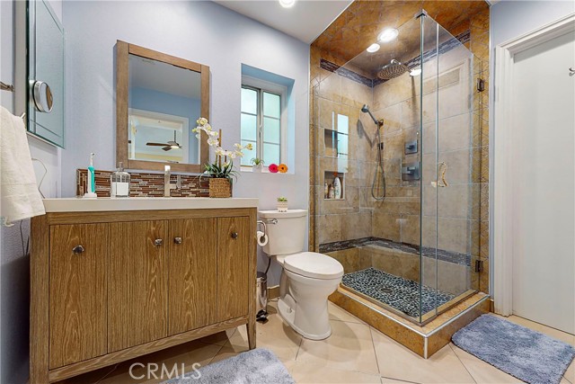 Remodeled upstairs bathroom with rain shower and handheld shower headand rock flooring.