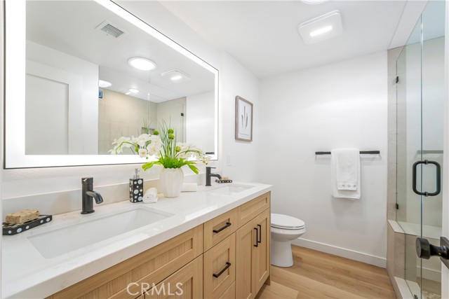Primary bath with double sinks, electrical outlet for bidet, lighted mirror, solatube, walk in shower with bench, frames glass door showered and hand shower.