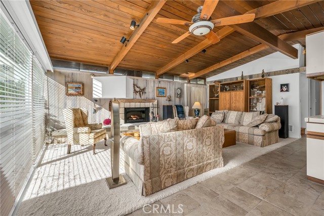 The lviing room with wood beam ceilings, tile floor, lights and ceiling fan.