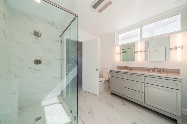 Main bedroom bathroom with clerestory windows, dual sinks and large glass enclosed shower.
