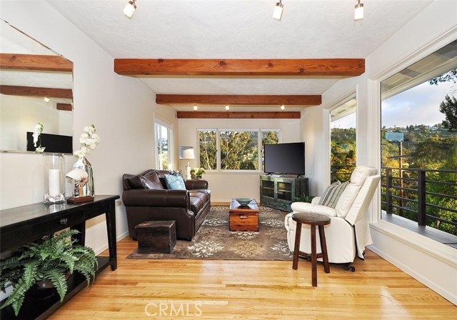 The family room with exposed wood beams overlooks a spectacular view of rolling hills.