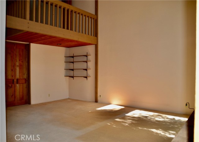 View towards lower level bedroom doors , shelved alcove and extension of second story bedroom with balcony.