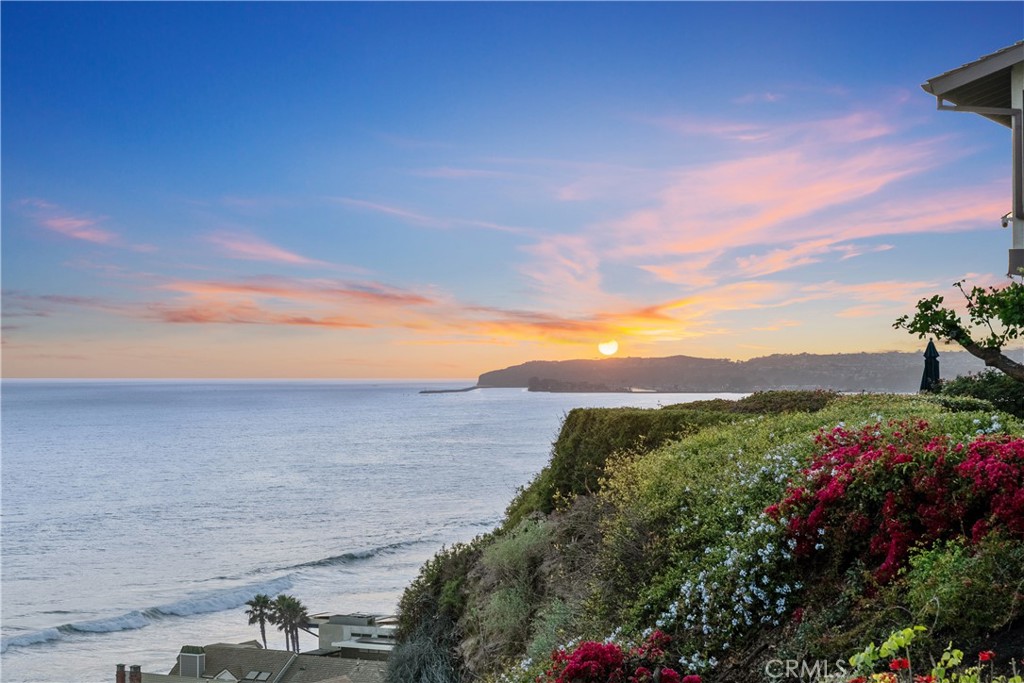 Step into coastal luxury with this stunning seaside property nestled atop the scenic bluffs of Capistrano Beach. This expansive, nearly 4,380-square-foot home offers an unparalleled living experience defined by the ever-changing panoramic views of the Pacific Ocean and Dana Point Harbor. Blending timeless elegance with modern convenience, the home boasts 4 ensuite bedrooms plus 2 half baths, and includes a gourmet chef’s kitchen with premium appliances, a large island, and a walk-in pantry. The adjacent dining room and living room open onto an expansive rear deck and offer commanding views of the ocean, providing a striking backdrop for relaxation or entertaining. A large laundry room and cozy den complete the first level. Take the stairs or the elevator to the second floor and find two primary and two large secondary bedrooms, each with vaulted ceilings and ensuite bathrooms. The second level also features a spacious office with a walk-in closet and a fabulous great room with ocean views and a stylish wet bar. Two garages provide parking for three cars, plenty of storage, and space for a workshop. The estate is ideally situated near the Dana Point Harbor and the Dana Point Lantern District, and the world-famous Trestles surf spot. This is coastal living at its most inviting.