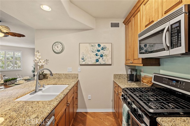 Granite counters, stainless appliances and warm wood cabinets in the kitchen - with breakfast bar and a view to living areas.