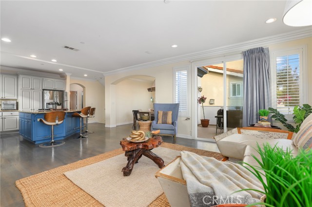 Different perspective of living space showing open kitchen and dining space in the far right with open balcony access from living and dining rooms.