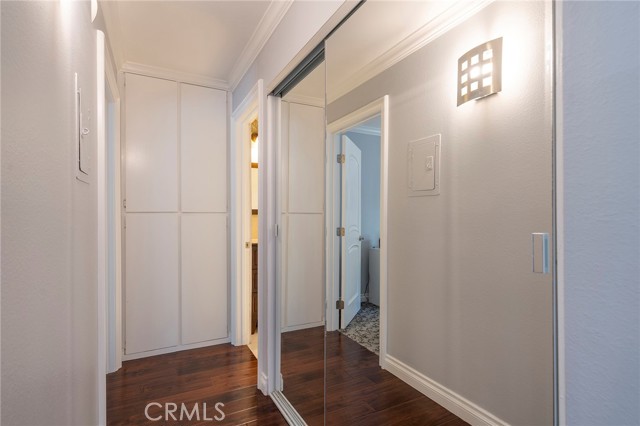 Hallway to the bedroom and bathroom with mirrored closet doors and extra linen closet space.