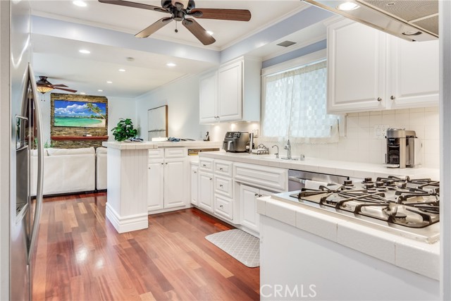 Kitchen with a coastal inspiration offers breakfast bar, white shaker cabinets, stainless appliances and hardwood floors