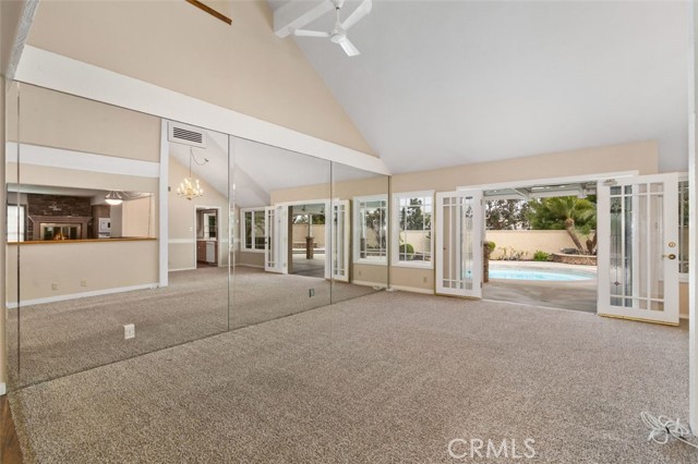 Spacious living room with ceiling fans and mirrored wall.