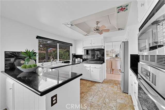 The kitchen boasts granite counters and a high backsplash, along with freshly painted cabinetry, a 5-burner gas stove, refrigerator, stainless steel oven and microwave & dishwasher.