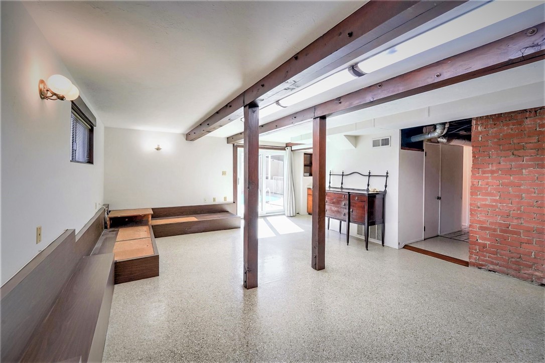 At the far end of the bonus room there is a sliding door leading out to the rear yard and the pool. Next to the sliding door to the right, there is a full wet bar.