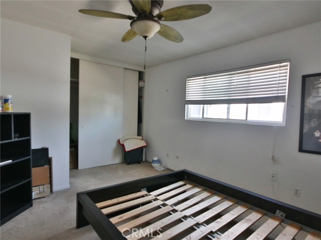 The secondary bedroom for the front unit showing the ceiling fan and closet.  To the left of the closet is an attached full bath.