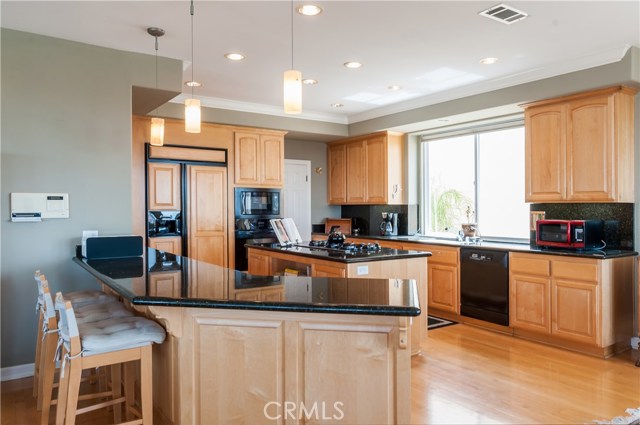 Big island kitchen has it all...polished black granite provides contrast to the natural maple cabinets.