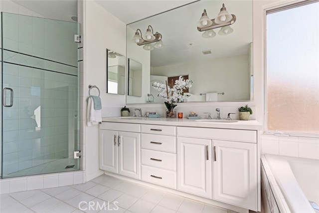 master bedroom bath with separate frameless glass shower enclosure, two sinks and built in cabinetry