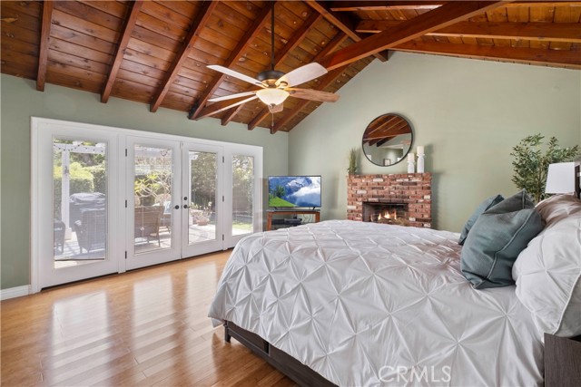 Primary bedroom with view of patio. Also showing off the wonderful wooded beamed ceiling and brick fireplace.