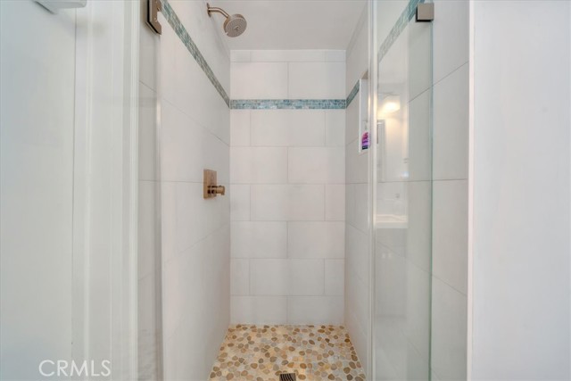 Updated shower in bedroom 3 with bronze shower fixture, a stone floor and glass doors