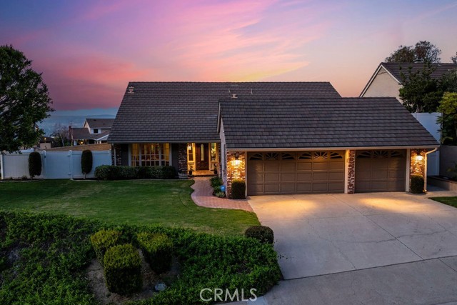 Dreaming of a single-level retreat with stunning views, a pool, and ample outdoor space? Welcome to 4401 E Ridge Gate Rd in the prestigious Rocky Point community of Anaheim Hills. Nestled on a coveted 10,800 square foot corner lot, this home is adjacent to a deeded 15,000 sqft verdant slope, providing unparalleled privacy and a lush, scenic backdrop maintained by the HOA. A charming brick path winds through a mature lawn, leading to an inviting entry. Inside, natural light floods the spacious living areas, where wall-to-wall windows frame snow-capped mountain views. The recently remodeled kitchen is a chef’s delight, featuring quartz countertops, an island, 6-burner cooktop, stainless steel Kitchen Aid appliances, soft-close cabinetry, pull-out drawers, and a farmhouse sink overlooking the BBQ area—perfect for effortless indoor-outdoor living. A dedicated beverage station with two appliance garages and a refrigerator makes mornings a breeze, whether enjoying coffee in the casual dining area or al fresco through the French doors. Unwind in the inviting family room, where an updated fireplace, built-in surround sound, and serene views create the perfect space to relax. Step outside to your private backyard oasis, where a sparkling pool and spa offer front-row seats to breathtaking city light views—ideal for entertaining or unwinding under the stars. The primary suite is a true retreat, with French doors leading to the backyard, elegant crown molding, high ceilings, and a remodeled en-suite bathroom featuring a soaking tub, walk-in shower, and dual vanities. Three additional spacious bedrooms share a renovated dual-vanity bathroom with a separate commode area. Additional highlights include luxury vinyl plank flooring in most living areas and the primary suite, a dedicated laundry area, crown moulding, chair rails ceiling fans, dual pane windows, and a 3-car garage with epoxy flooring & ample storage. Located in the award-winning Nohl Canyon Elementary, Cerro Villa Middle, Villa Park High, and minutes from top-rated dining, shopping, and convenient freeway access (91 & 55)—this home is the complete package. Don’t miss this rare opportunity for single-story living with stunning views, a remodeled interior, and an entertainer’s backyard!