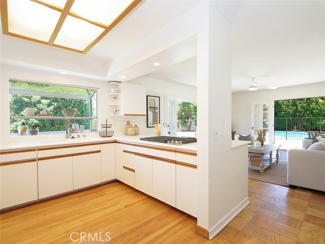 Open plan kitchen with garden window, new cooktop, glowing floors.